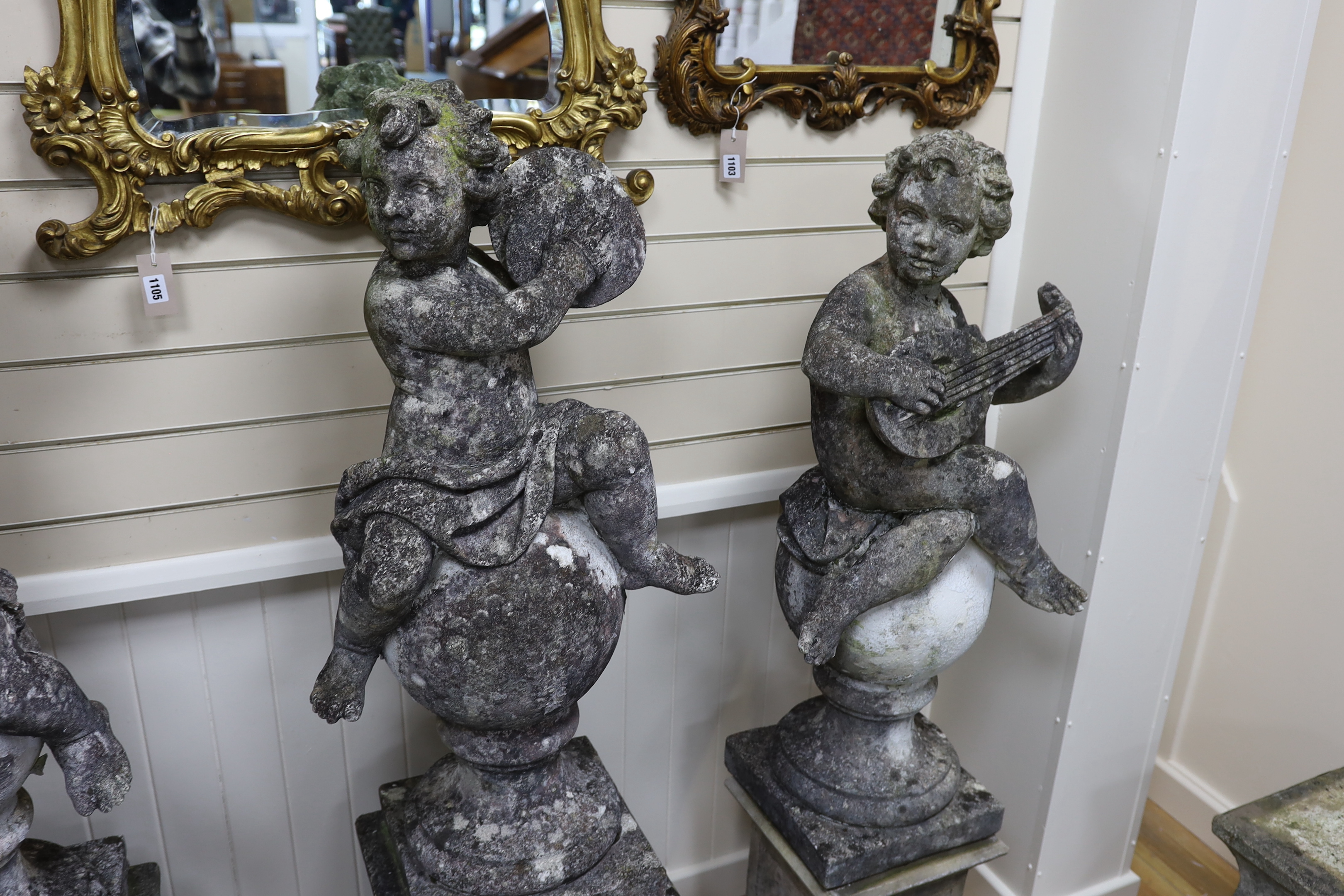 A set of four reconstituted stone garden ornaments formed as musical putti, on two differing pairs of square plinth bases, largest height 150cm